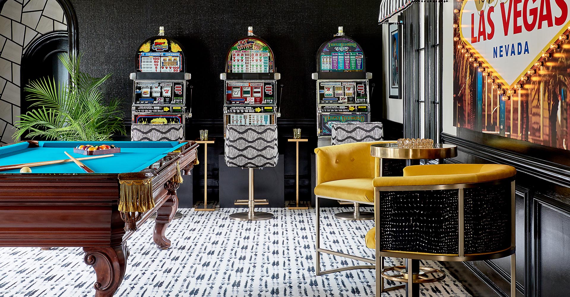 A pool table in a room with black walls and gold accents.